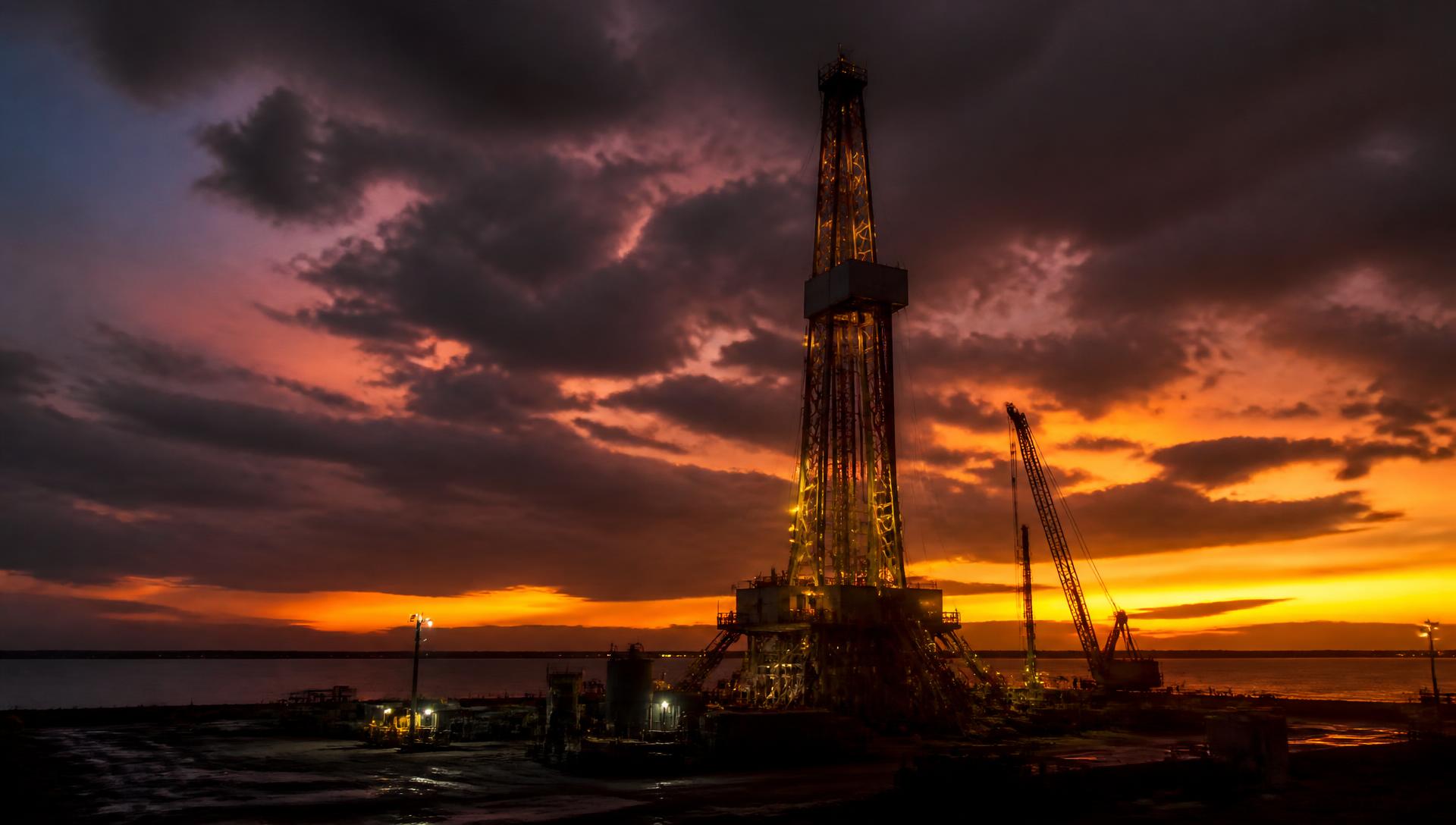 Taladro de perforación petrolera en operación al atardecer